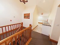 Stairs leading to the kitchenette with washing machine, tumble dryer, dishwasher and fridge.