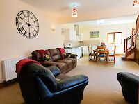 The open plan kitchen and lounge. Cosy sofas with throws and cushions.