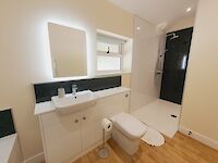 Sleek bathroom showing walk in shower, Sink, Toilet, heated mirror with light and underfloor heating.