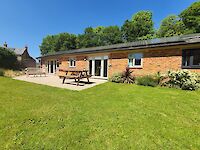 Lush green garden and patio with hot tub of Maplewood with seating area and scenic views.