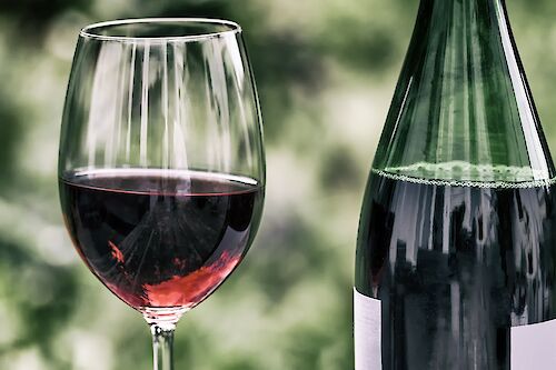 Image of a glass of summer red wine and a bottle next to it.