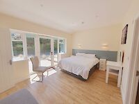 King bedroom of Maplewood featuring patio doors to the garden and hot tub. Dressing table, chair and sofa bed on the ground floor.