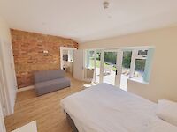 King bedroom of Maplewood featuring patio doors to the garden and hot tub. Dressing table, chair and sofa bed on the ground floor.