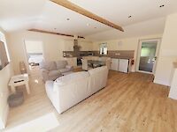 Open plan lounge and dining area of Maplewood with fully equipped kitchen, smart TV and patio doors leading to the garden