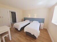 Twin bedroom of Maplewood featuring fitted wardrobes. Dressing table, chair and underfloor heating.